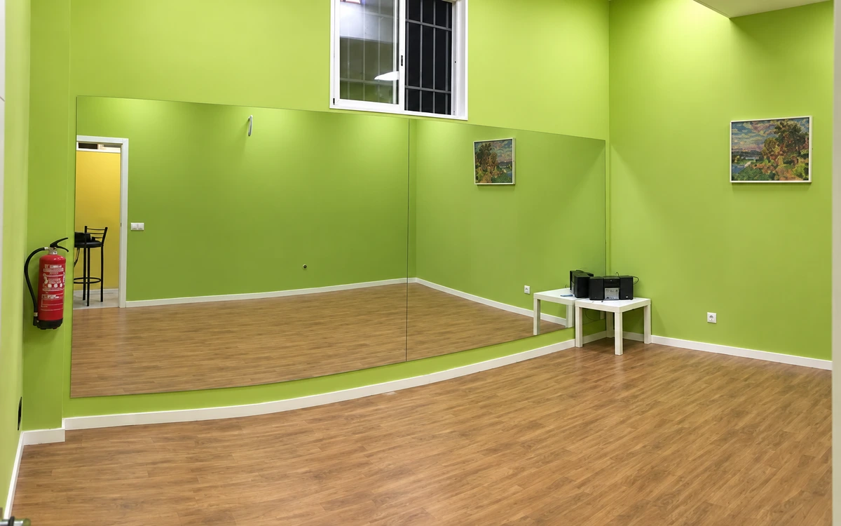 Sala Verde: espejo, ventana alta y equipo de música sobre una mesa blanca